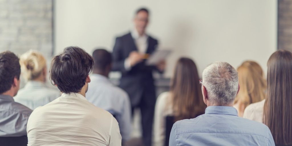 Rear view of large group of business people on a training. Focus is on foreground.